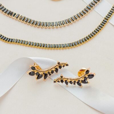 A sophisticated gold jewelry set displayed on a white ribbon, highlighting elegance and luxury.