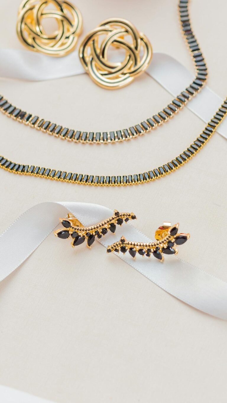 A sophisticated gold jewelry set displayed on a white ribbon, highlighting elegance and luxury.