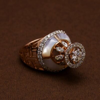 Luxurious gold ring with diamonds and pearl detail on a rich brown surface, showcasing elegance.