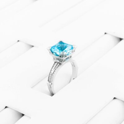 Stunning silver ring featuring a vibrant blue gemstone on a white woven surface. Perfect for jewelry showcases.